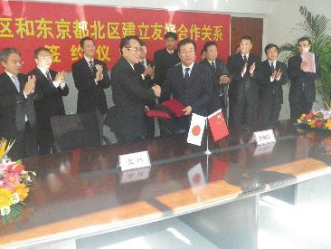 写真:花川與惣太北区長(左)と握手をする王少峰西城区代区長