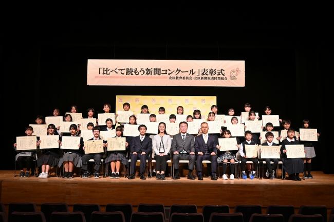 写真：表彰状を見せながら記念撮影する子供たちと関係者ら