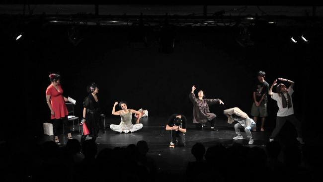 写真：黒い舞台の上でポーズを取る役者たち