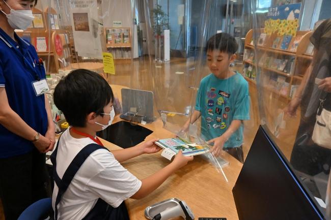 写真：貸し出す本を手渡す子ども1日図書館員