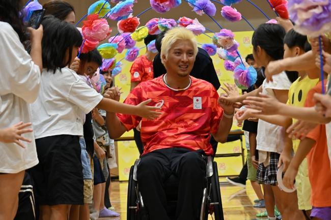 写真：子供たちに囲まれながら移動する小川選手