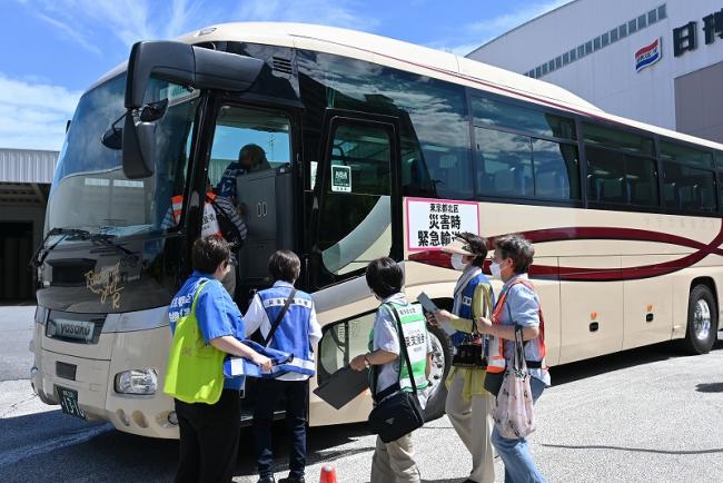 写真：日本製紙物流倉庫前からバスに乗車する訓練者の様子