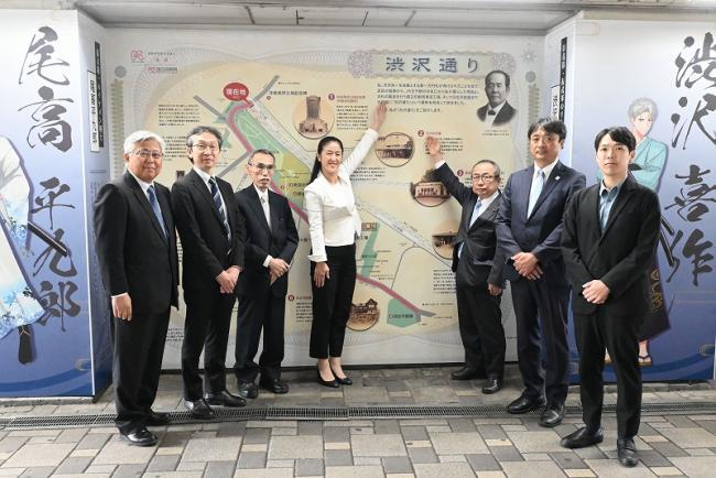 写真：渋沢通りの案内板前で記念撮影する関係者ら