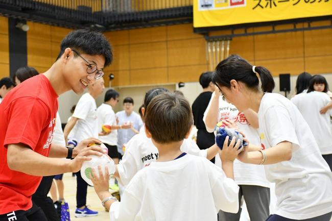 写真：子供たちと一緒に紙風船を持つアスリートら